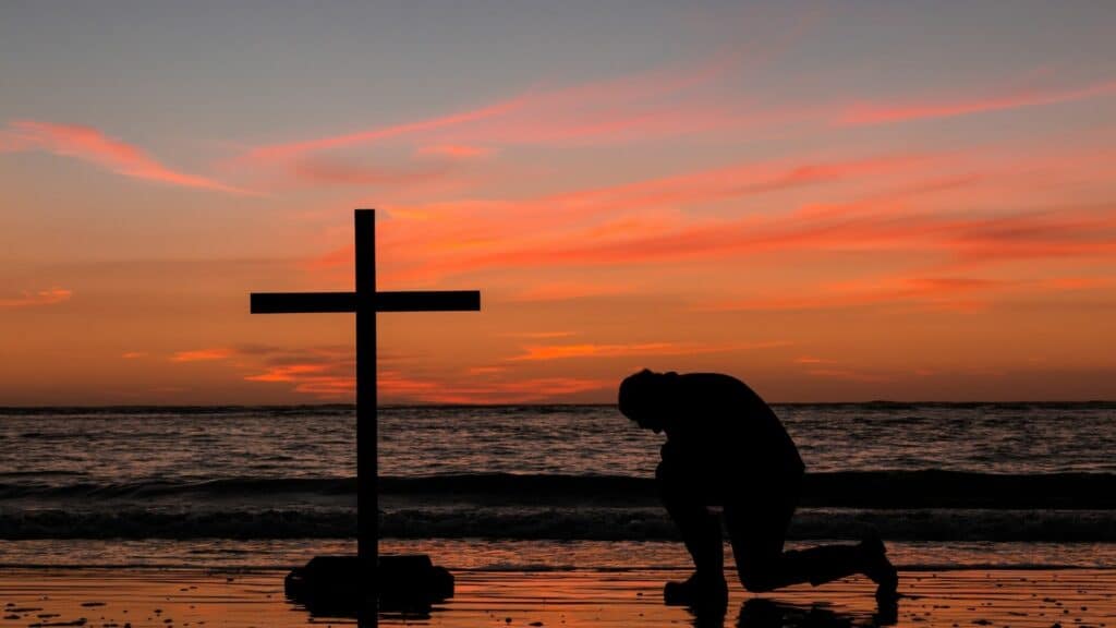 man praying with cross