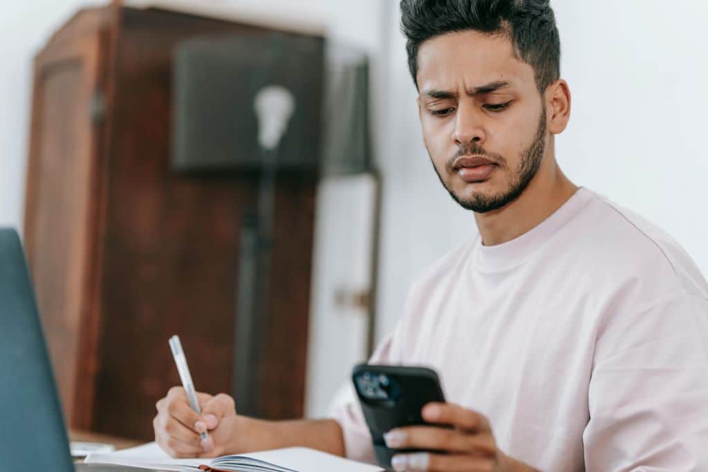 How Much Average Screen Time is Good for Teens? A Curation 43 Heroes: Teenager distracted by phone while doing homework